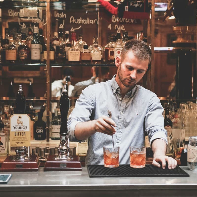 Professionell bartender som blandar drinkar i en autentisk bar med premium-sprit